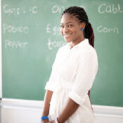 African-American teacher smiling while standing near blackboard